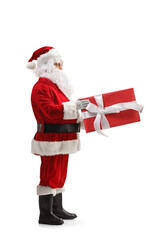 Sticker - Full length profile shot of santa claus holding a big present