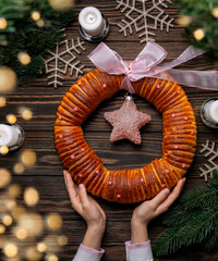 Wall Mural - Homemade baked sweet Christmas wreath pie holded by the girls hands. Festive background with traditional winter decorations and lights.