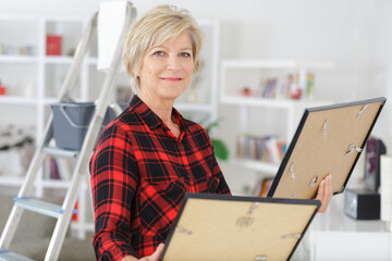 mature woman holding two picture frames