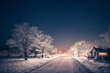 Winter snowy small cozy street with lights in houses, falling snow town night landscape. Winter holidays night time backdrop. Merry Christmas vintage retro illustration background.