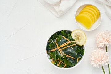 Wall Mural - top view flat lay. overhead salad laminaria Kelp or wakame seaweed salad in bowl on white table background with copy space. salad laminaria Kelp or wakame seaweed salad food              