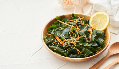 Wall Mural - close up salad laminaria Kelp or wakame seaweed salad in wood bowl on white table background with copy space. salad laminaria Kelp or wakame seaweed salad food