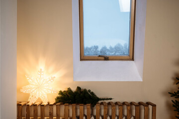 A window in the wall in the bedroom with a view of winter. The walls are beige, the room has small windows. Looking outside to see the view of the forest and snow.