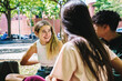 © Guillem de Balanzó - Content diverse students chatting on lawn in campus after studies