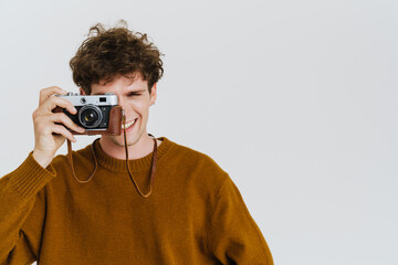 Wall Mural - Young stylish curly man in brown sweater with vintage camera