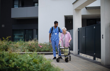 Wall Mural - Caregiver walking with senior woman client in front of nurishing home.