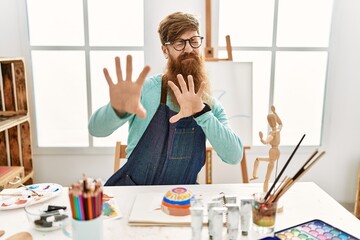 Canvas Print - Redhead man with long beard painting clay bowl at art studio disgusted expression, displeased and fearful doing disgust face because aversion reaction. with hands raised