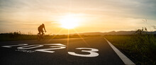 New Year 2023 Or Start Straight And Beginning Concept.silhouette Of Blurry Man Ride On Bike And Word 2023 Start Written On The Road At Sunset.Concept Of Challenge Or Career Path,business Strategy.