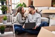 © Krakenimages.com - Man and woman using laptop sitting on floor with dog at new home
