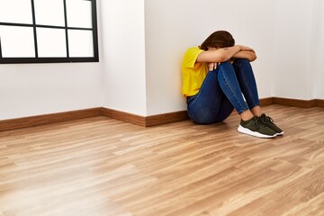 Canvas Print - Young woman sitting on floor crying at empty room