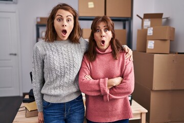 Canvas Print - Two women working at small business ecommerce scared and amazed with open mouth for surprise, disbelief face