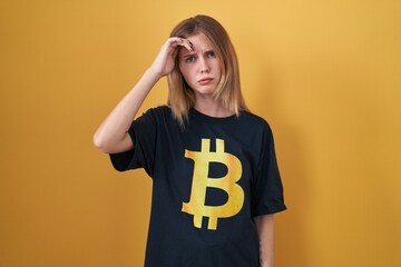 Canvas Print - Blonde caucasian woman wearing bitcoin t shirt worried and stressed about a problem with hand on forehead, nervous and anxious for crisis