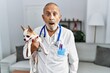 © Krakenimages.com - Mature veterinarian man checking dog health scared and amazed with open mouth for surprise, disbelief face