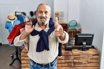 Wall Mural - Handsome senior man holding shopping bags at boutique shop pointing fingers to camera with happy and funny face. good energy and vibes.