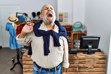 Canvas Print - Handsome senior man holding shopping bags at boutique shop angry and mad screaming frustrated and furious, shouting with anger. rage and aggressive concept.