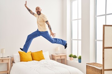 Wall Mural - Young bald man jumping on bed at bedroom