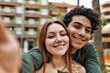 Young interracial couple smiling happy and hugging make selfie by the camera at the city.