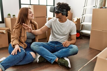 Canvas Print - Young couple smiling happy playing with 3d vr glasses at new home.