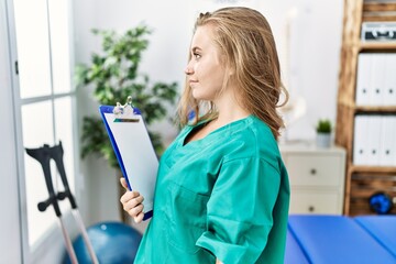 Canvas Print - Young caucasian woman working at pain recovery clinic looking to side, relax profile pose with natural face and confident smile.