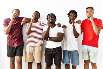 Canvas Print - Young african group of friends standing together over isolated background with hand on chin thinking about question, pensive expression. smiling with thoughtful face. doubt concept.