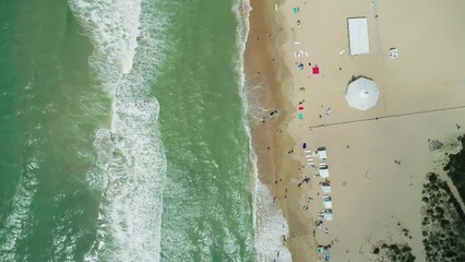 Wall Mural - Aerial over the sandy beach with many people and azure water on a sunny summer day. Waves crashing to the shore. Relaxing calm atmosphere