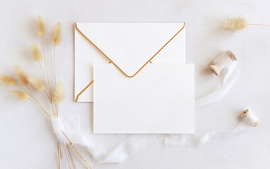 Wall Mural - Card and envelope near silk ribbons and dried hare's tail grass top view on white, boho mockup