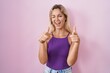 © Krakenimages.com - Young blonde woman standing over pink background pointing fingers to camera with happy and funny face. good energy and vibes.