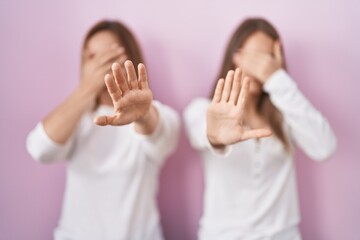 Canvas Print - Middle age mother and young daughter standing over pink background covering eyes with hands and doing stop gesture with sad and fear expression. embarrassed and negative concept.