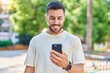 © Krakenimages.com - Young hispanic man smiling confident using smartphone at park
