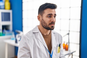 Sticker - Young hispanic man wearing scientist uniform with serious expression at laboratory