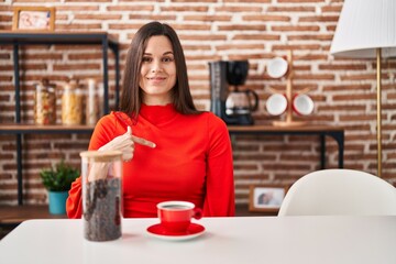 Poster - Young hispanic woman drinking coffee at home pointing finger to one self smiling happy and proud