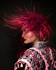 Fashion female portrait with avantgarde hair style at black background. Woman in matador suit with bred hair. Expressive shot of hairdressing art.