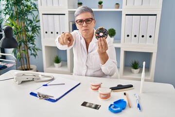 Sticker - Middle age dentist woman holding chocolate doughnut smiling with hand over ear listening and hearing to rumor or gossip. deafness concept.