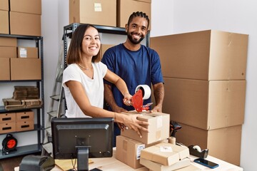 Poster - Man and woman business partners packing package using tape at storehouse