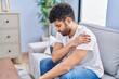 © Krakenimages.com - Young arab man suffering for shoulder injury sitting on sofa at home