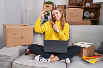 Wall Mural - Young blonde woman having video call holding key at new home