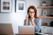 © sepy - Businesswoman using mobile phone in front of laptop while working from home