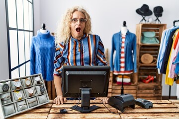 Poster - Middle age blonde woman working as manager at retail boutique afraid and shocked with surprise expression, fear and excited face.