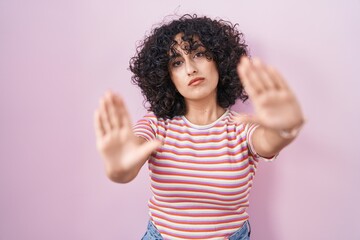 Canvas Print - Young middle east woman standing over pink background doing frame using hands palms and fingers, camera perspective