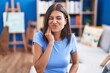 © Krakenimages.com - Brunette young woman sitting on the sofa at home touching mouth with hand with painful expression because of toothache or dental illness on teeth. dentist
