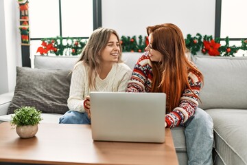 Poster - Woman couple using laptop and drinking coffee sitting by christmas decor at home