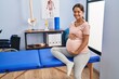 © Krakenimages.com - Young latin woman pregnant patient sitting on massage table at clinic