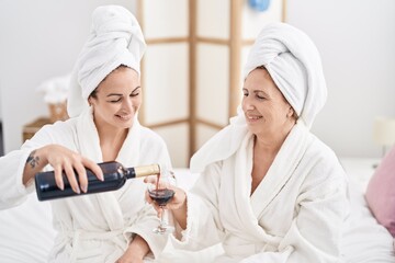 Poster - Mother and daughter wearing bathrobe drinking wine at bedroom