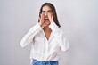 © Krakenimages.com - Young brunette woman wearing glasses shouting angry out loud with hands over mouth