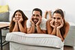 © Krakenimages.com - Three hispanic friends smiling happy with hands on face lying on the sofa at home.