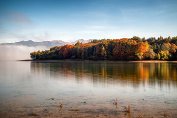 Wall Mural - Long exposure photo of colorful autumn leaves on trees on coast of lake Liptovska Mara, Slovakia: Beautiful waterscape