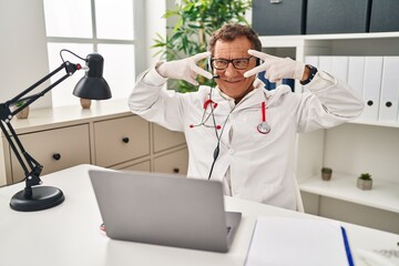 Sticker - Senior doctor man working on online appointment doing peace symbol with fingers over face, smiling cheerful showing victory