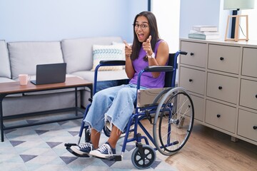 Sticker - Young hispanic woman sitting on wheelchair at home pointing fingers to camera with happy and funny face. good energy and vibes.