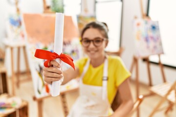 Canvas Print - Adorable girl smiling confident holding diploma at art studio