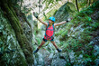 © Westend61 - Woman with arms outstretched climbing mountain in forest